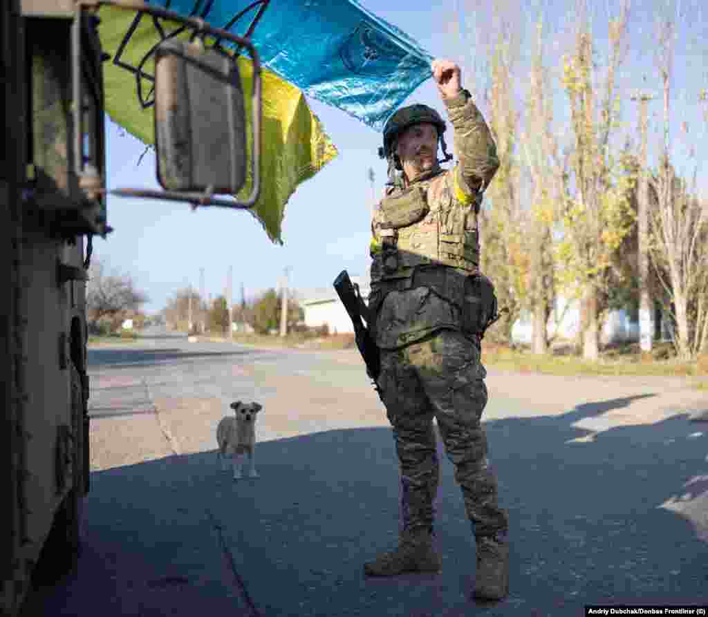 Солдат показує збережений у боях прапор України, чиї кольори виблискують під промінням сонця, яке вже починає сідати над звільненою від російських окупантів Снігурівкою. Місто, розташоване на стратегічній висоті на самому півдні Миколаївщини і за 50 кілометрів від Херсона, було окупованим з початку березня 2022 року