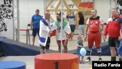 Iranian weightlifter Mustafa Radschaie Langrudi (center) has been banned by his country after being photographed shaking hands with a member of the Israeli team at a competition in Poland.
