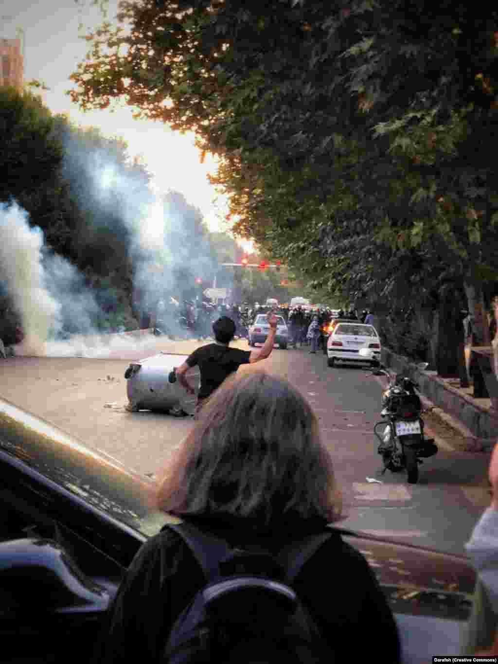 A September 2022 photo shows a young woman watching violent protests in Tehran following the death of Mahsa Amini. Throughout the widespread unrest that followed the September 2022 death of Amini while in the custody of the morality police, increasing numbers of women opted not to wear their hijabs. The head scarves have been mandatory in Iran since shortly after the 1979 Islamic Revolution. 