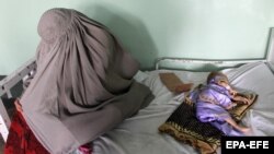 An Afghan woman sits next to child suffering from malnutrition and other diseases while receiving treatment at the Mirwais hospital in Kandahar in May.