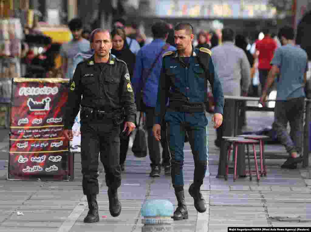 Two policemen walk through Tehran on July 16. The officer on the left is wearing the standard green uniform that is worn by units of the morality police. 