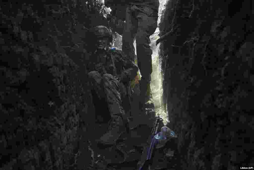 As the shelling continues, a Ukrainian soldier hunkers down in a trench. 