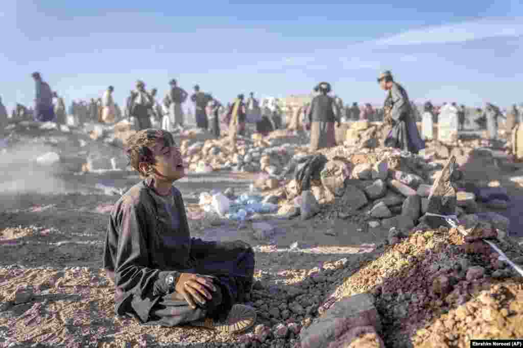 An Afghan boy mourns next to the grave of his little brother on October 9 as rescuers dig underneath the rubble of flattened homes. The child died two days earlier in an earthquake that hit the Zindah Jan district of western Afghanistan's Herat Province. A 6.3-magnitude earthquake struck the same area on October 11, destroying 700 homes in the village of Chahak, which had been untouched by the tremors of previous days. 
