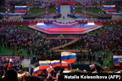 Люди слушают выступление президента России Владимира Путина (в центре сцены) во время патриотического концерта, посвященного предстоящему Дню защитника Отечества, на стадионе Лужники в Москве 22 февраля 2023 года