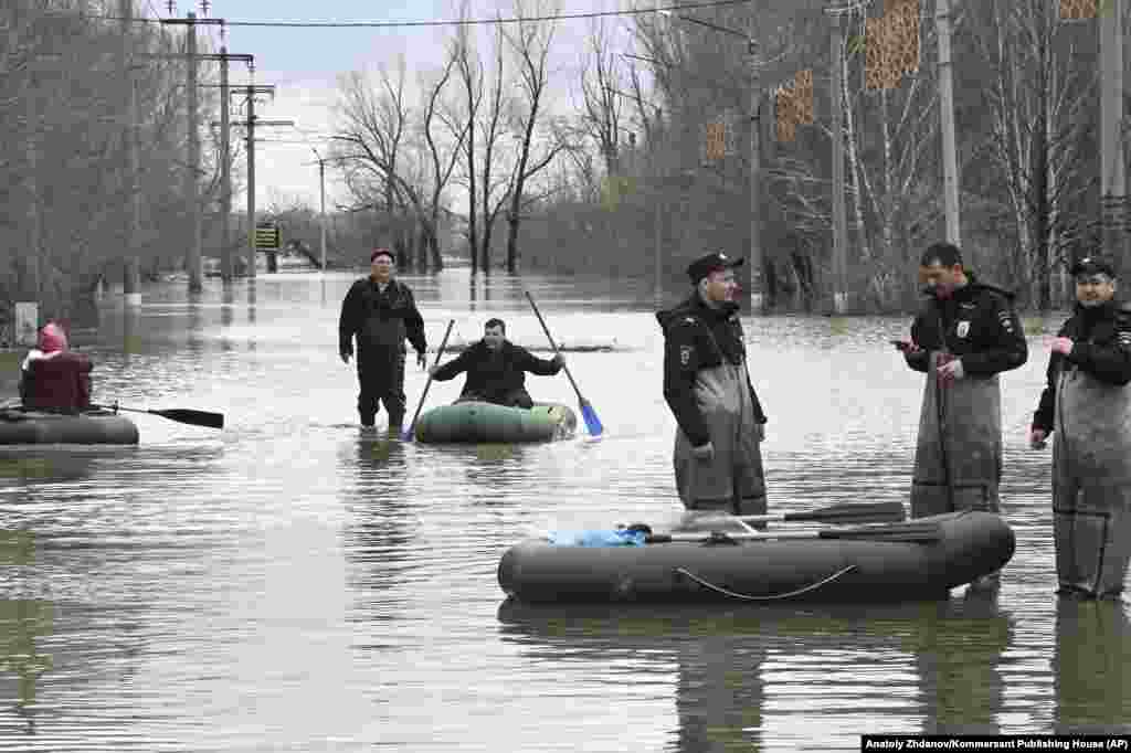 Police officers stand watch while people in Orsk rely on rubber rafts to navigate the floodwaters. 