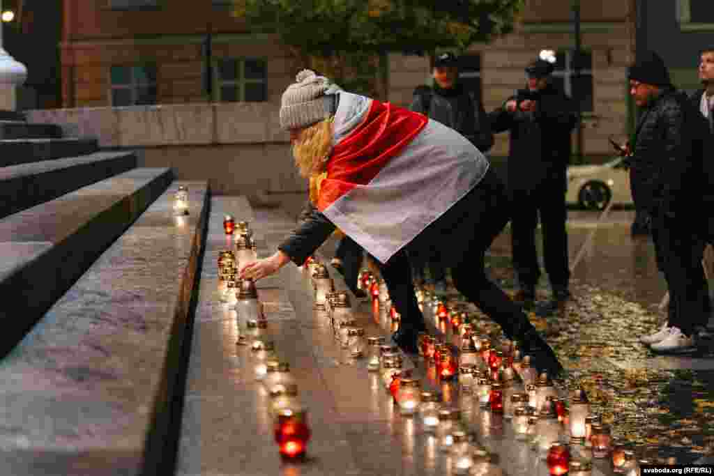 A woman wearing the white-red-white flag of the Belarusian Democratic Republic places a candle on the steps of Vilnius city hall in Lithuania on October 29. A total of 132 candles were lit in memory of Belarusian intellectuals, poets, politicians, artists, and scientists who were executed on October 29–30, 1937. 