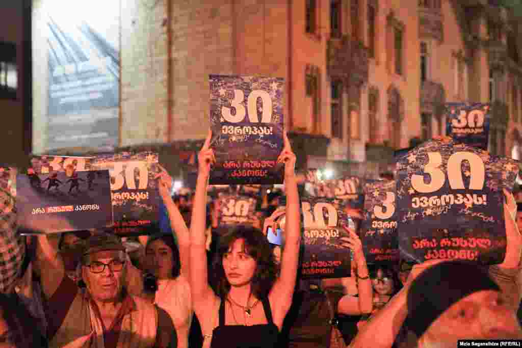 Protesters hold up signs that say, "Yes to Europe" and "No to Russian law."