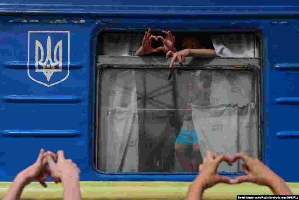 Family members and friends make the heart symbol as the evacuation train begins its departure from the platform. 
