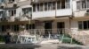 Жінка дивиться на пошкоджене вікно своєї квартири на другому поверсі будинку на вулиці Марченка. Ця вулиця постраждала в Новофедорівці найбільше, оскільки найближче розташована до військового аеродрому