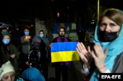 Iranian and Ukrainian nationals hold Ukrainian national flags as they gather in front of the Ukrainian Embassy in Tehran on February 26.