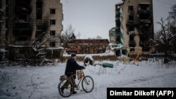 A man pushes his bike next to destroyed residential buildings in Borodyanka, near Kyiv, on December 4.