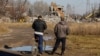 Two men watch workers removing the debris of the building in Makiyivka where the Russian soldiers were housed when the strike hit on New Year's Eve.