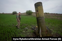 A Ukrainian solder walks near the tail section of a Tochka U ballistic missile in the Kharkiv region in April.