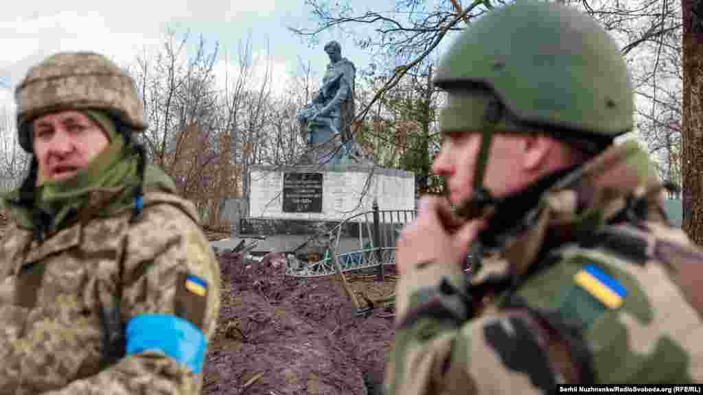 Украинские военные на фоне поврежденного памятника павшим во время Второй мировой войны 