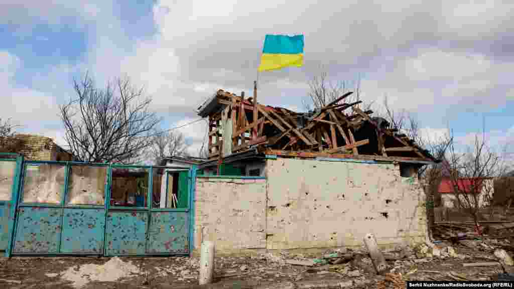 Украинский флаг над серьезно пострадавшим во время боев домом 