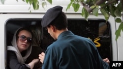 An Iranian morality policeman speaks with a woman siting in a police vehicle after she was arrested for failing to observe the mandatory Islamic dress code. (file photo)