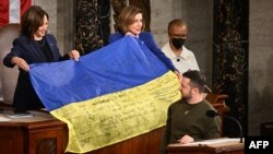 Ukrainian President Volodymyr Zelenskiy gives a Ukrainian national flag to U.S. House Speaker Nancy Pelosi and Vice President Kamala Harris (left) during his address the U.S. Congress at the U.S. Capitol in Washington, D.C. on December 21.