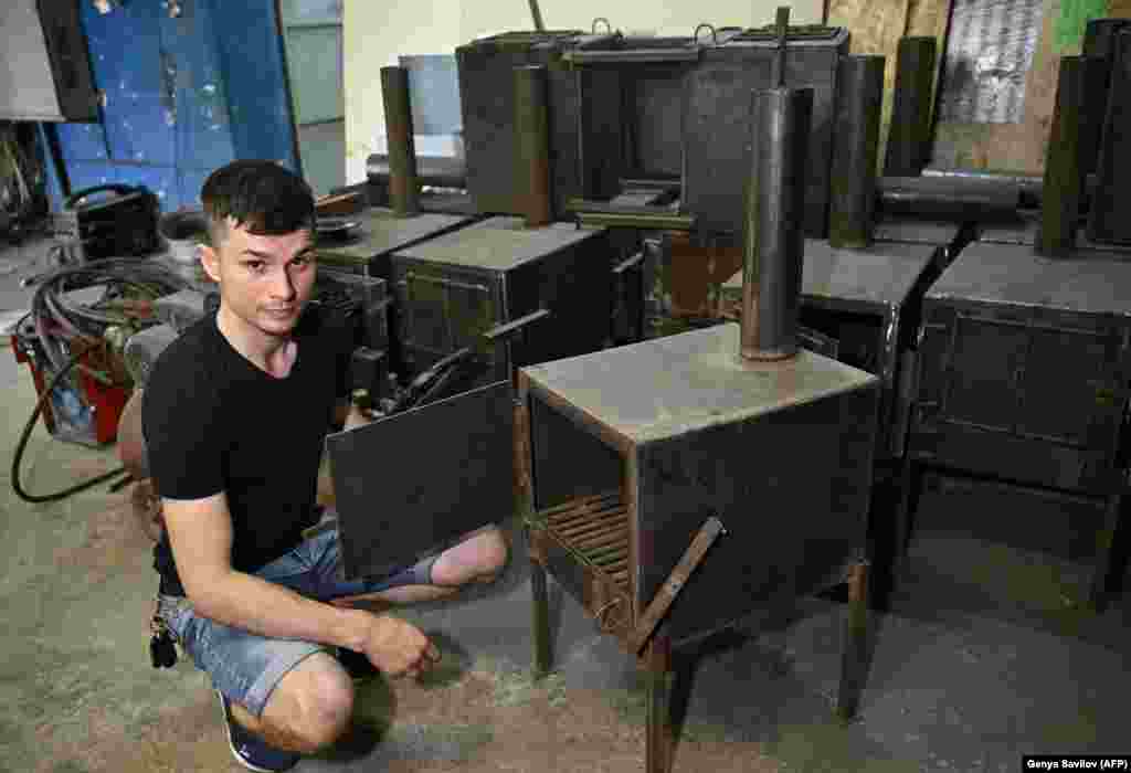 Коваль Антон Заїка показує новостворену піч у своїй майстерні в Сумах, фото від 1 серпня 2022 року. Дров’яні печі 32-річний чоловік розробив спеціально для використання в траншеях як джерело тепла та як пристрій для приготування їжі