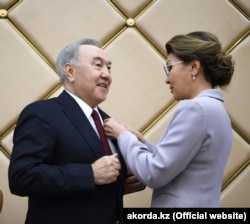 Dariga Nazarbaýewa öz kakasy Nursoltan Nazarbaýewiň döşüne «Hormatly senator» diýen nyşany dakýar. 2019-nji ýylyň 6-njy iýuny.