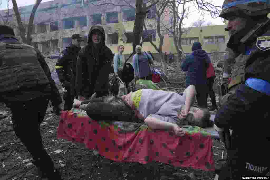 Еріктілер жараланған жүкті әйелге көмектесіп жатыр. 