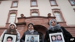 Szíriai nők tartják hazájukban meggyilkolt rokonaik képét az ítélethozatal előtt a koblenzi bíróság épületénél. 2022. január 13. 