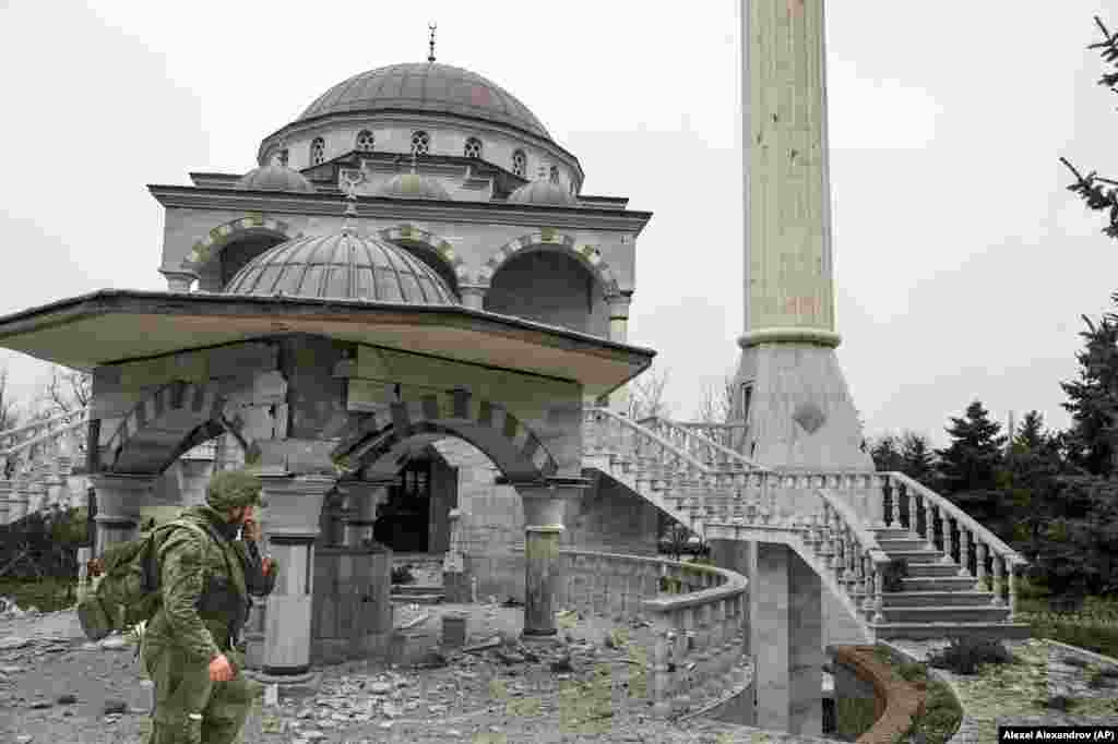 A pro-Russian militant walks past the battle-damaged mosque in April 2022. 