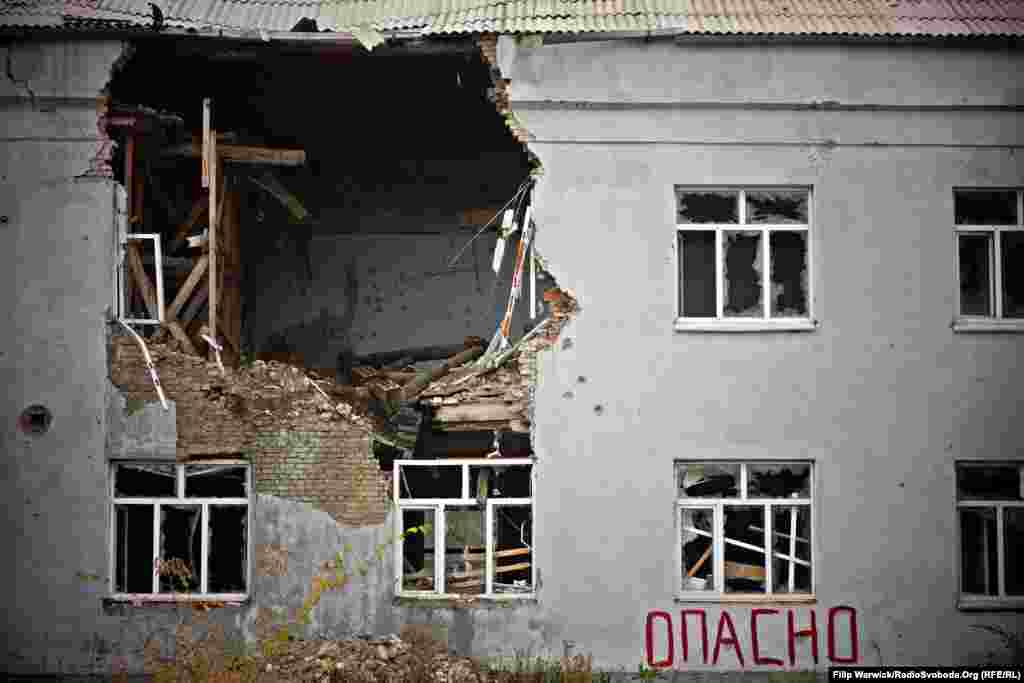 Луганск облысындағы қираған үйлер қақтығыс жүріп жатқанын еске түсіріп тұр. Украинаның шығысында мұндай үйлерге де көз үйрене бастады. Үй қабырғасындағы жазу ғимараттың қирағалы тұрғанын, ішіне кіру қауіпті екенін ескертеді. 