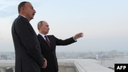 Azerbaijan -- Russia's President Vladimir Putin (L) and his Azerbaijani counterpart Ilham Aliyev (R) speak as they walk in Baku, on August 13, 2013. 