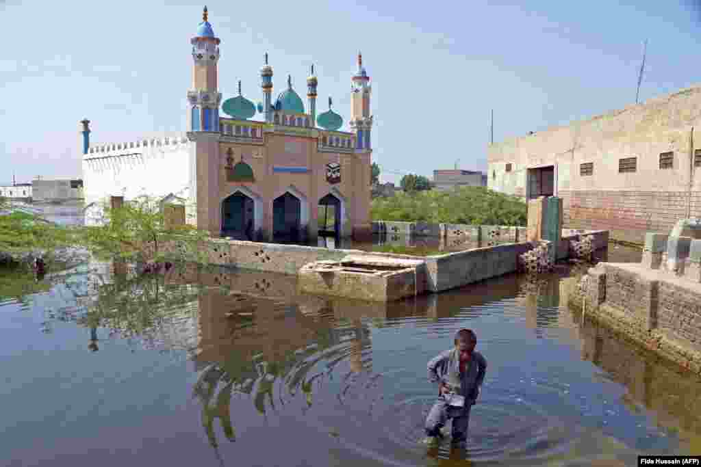 A boy wades through floodwaters in the Jaffarabad district in central Pakistan on September 19. The 2022 monsoon season has dumped more than three times the average rainfall on Pakistan, leading to vast swaths of the country being submerged. 