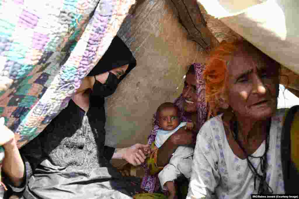 Jolie wears a face mask as she speaks with a mother living in a makeshift shelter in the southern Dadu district. The International Rescue Comittee (IRC) said in a statement before the actress's September 20 visit that Jolie would be there "to witness and gain understanding of the situation, and to hear from people affected directly about their needs, and about steps to prevent such suffering in the future."