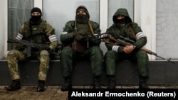 Armed men wearing masks are seen in the center of Luhansk on November 22.