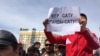 Участник митинга держит плакат с надписью: &quot;Продать землю - значит продать родину&quot;.