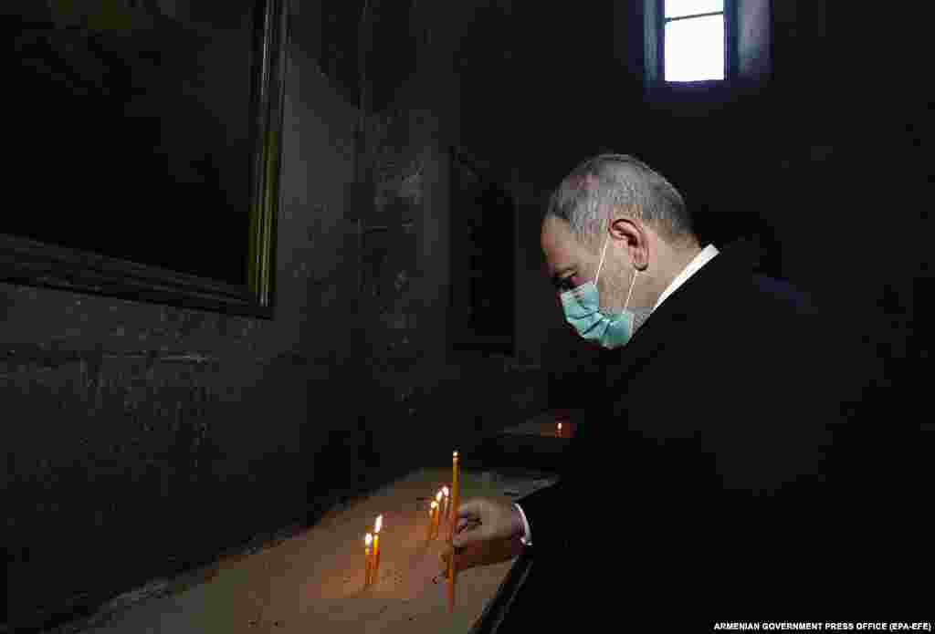 Pashinian lights a candle inside a church in a military cemetery in Sisian on December 21. The Armenian prime minister was openly snubbed by a priest who refused to shake his hand and appeared to usher him out of the Sisian church.