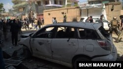 Kabul residents walk past the ruins and rubble aftre a blast at voter-registration center on April 22.