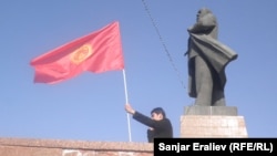 A man waves a Kyrgyz flag next to a statue of Soviet leader Vladimir Lenin in central Osh. City authorities took down the statue in June.