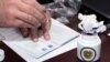Armenia - A member of the Central Election Commission puts a sample passport stamp designed to prevent multiple voting in elections, Yerevan, 12Feb2013.