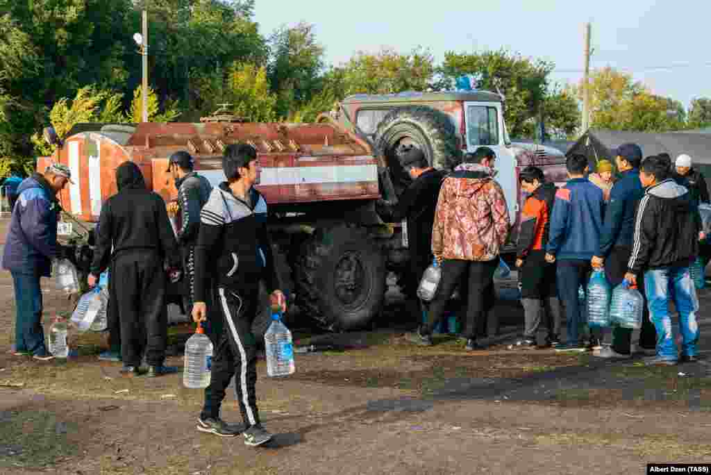 Мигранты наполняют водой пластиковые бутылки в палаточном городке. 22 сентября 2020 года.
