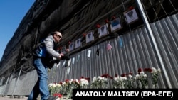 Мужчына ўскладае кветкі да імправізаванага мэмарыялу ў памяць пра загінулых мэдыкаў ля шпіталя ў Санкт-Пецярбургу, 1 траўня
