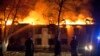 Riot police look on as firefighters try to extinguish fires after mass protests in the town of Ismayilli on January 24.