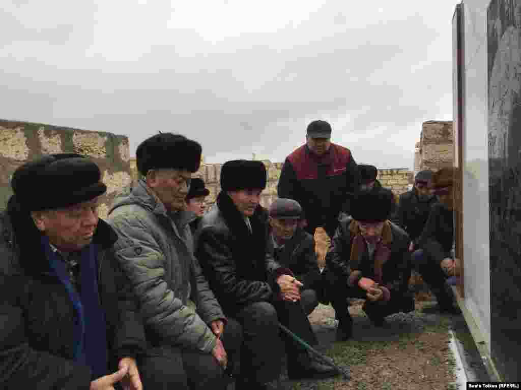 Мужчины слушают слова молитвы на кладбище на поминках по жертвам разгона демонстрации нефтяников в Жанаозене. 