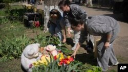 People lay flowers and toys at the site of Russia's deadly missile attack that hit residential housing on April 24, killing 12 civilians and injuring 87 in Kyiv, on April 25.