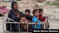 A displaced Iraqi woman and children are transported in a cart.
