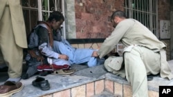 People attend to a man injured in a blast in the Afghan city of Mazar-e Sharif on March 11.