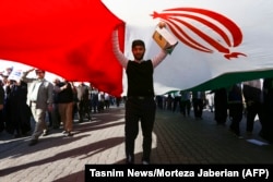A pro-government demonstrator stands under an Iranian flag during a march in Iran's southwestern city of Ahvaz on January 3.