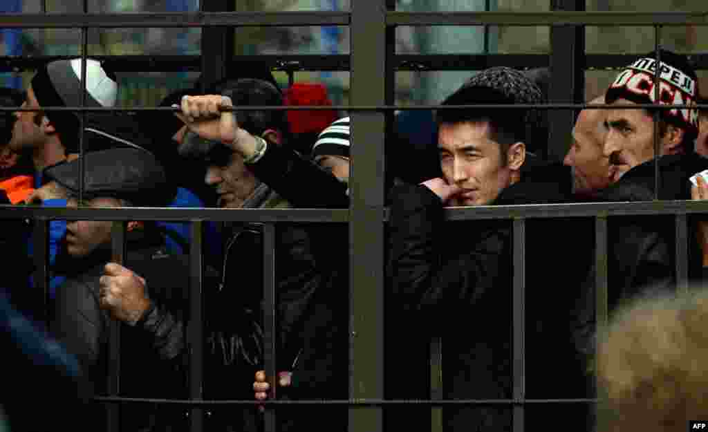 Migrant workers line up in a fenced holding area outside Russia's Federal Migration Service office in Moscow to apply for work permits in October 2013. 