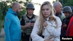 A resident holds her dog at the site of an apartment building damaged during Russian drone and missile strikes on the town of Smila in Ukraine's Cherkasy region.