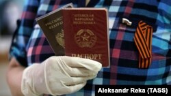 A woman holds a Russian passport and a passport from the Luhansk separatist region at a polling station in Donetsk in June 2020.