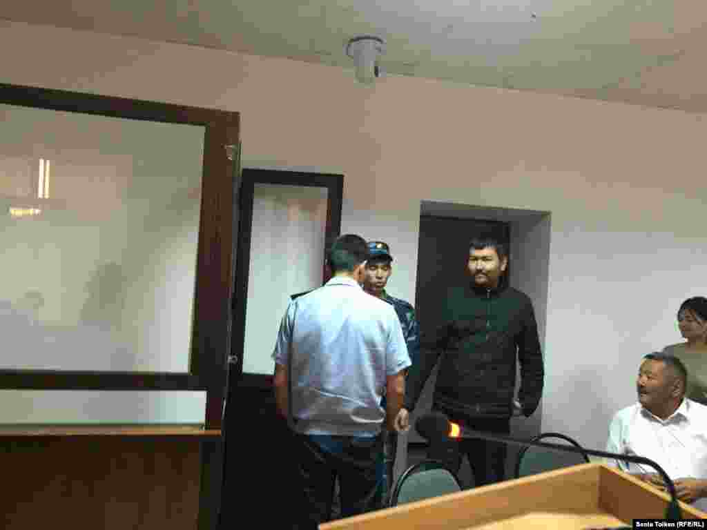Находящегося под стражей гражданского активиста Талгата Аяна полицейские доставили в зал суда. 
