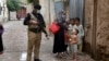 A police officer stand guard while a health-care worker administers a polio vaccine to a child as part of a national inoculation campaign. (file photo)