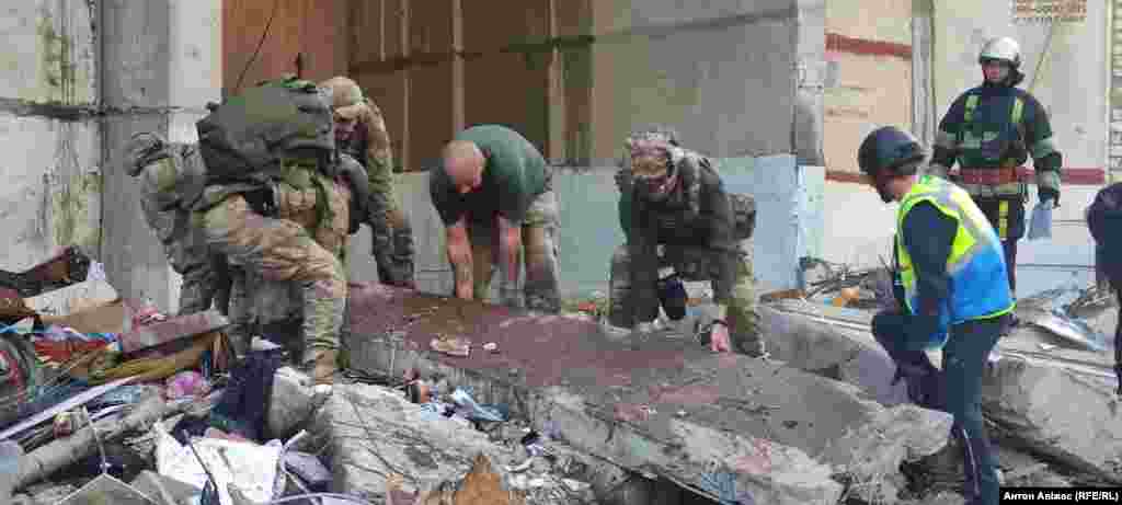 Rescuers attempt to lift a concrete panel of a shattered apartment that appears to be covered in blood. At least five Russian glide bombs were reported to have been used in the strikes. 